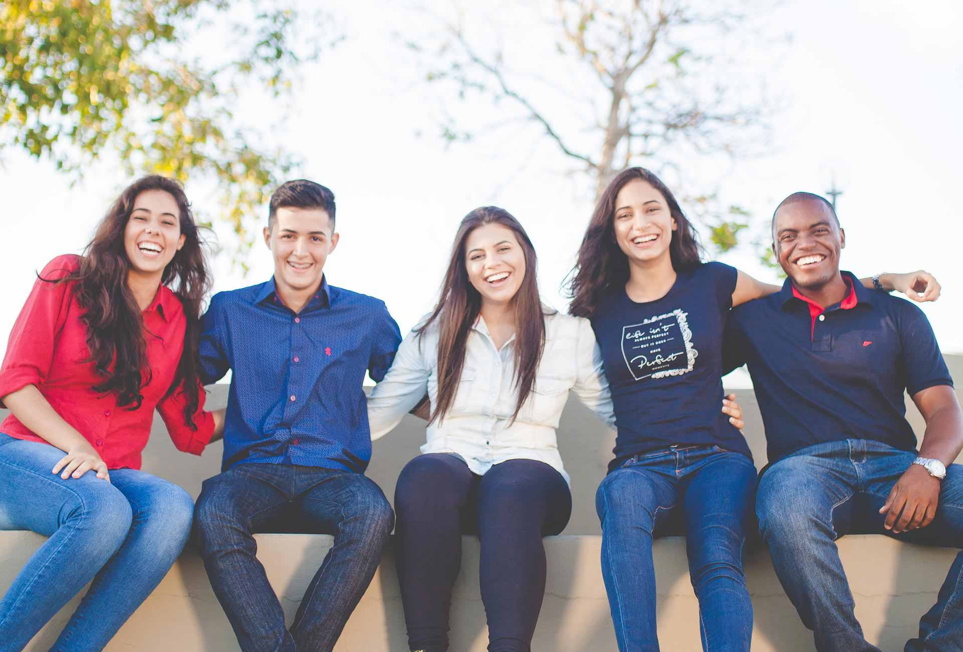 Students sitting outside on a bench interlocking arms